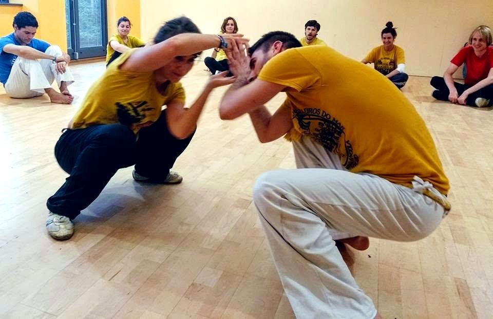 Two students playing Capoeira Angola low to the ground