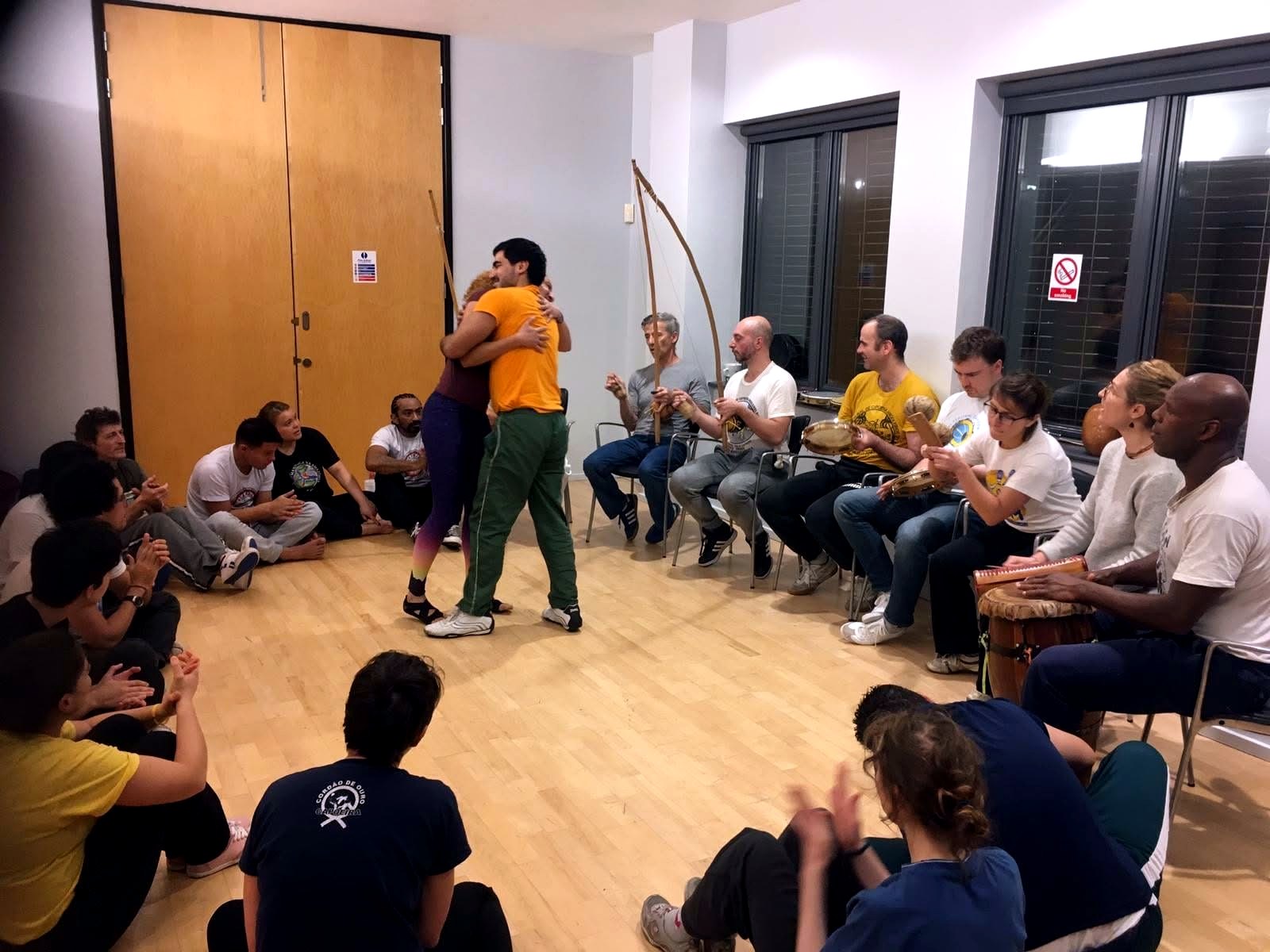 Capoeira Angola roda with students clapping and musicians playing