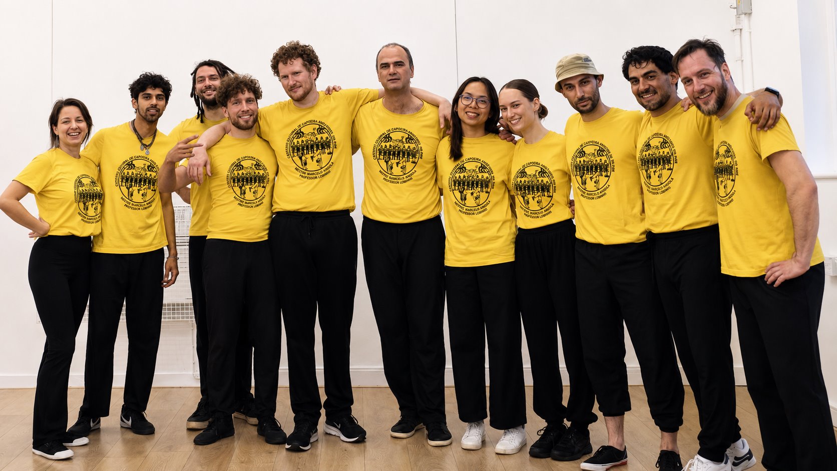 Oxford Capoeira Society students and teachers smiling together in yellow group shirts