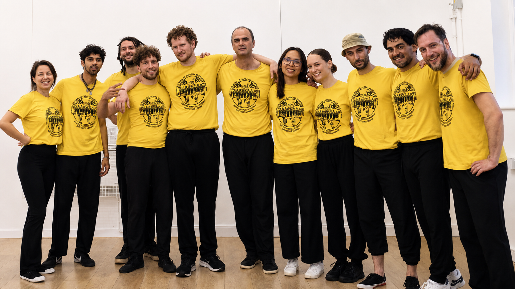 Oxford Capoeira Society students and teachers smiling together in yellow group shirts
